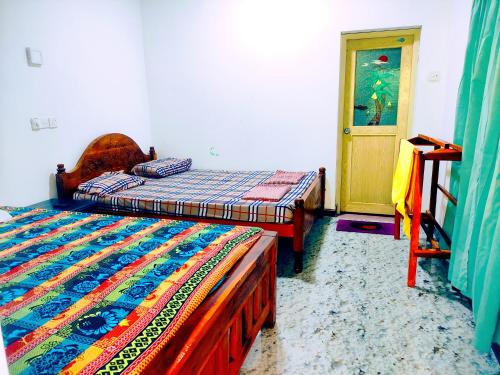 a bedroom with two beds and a door to a room at Deer Garden Guest in Polonnaruwa
