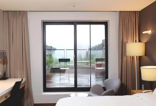 a hotel room with a sliding glass door with a balcony at Eden Paradise Hotel in Icheon