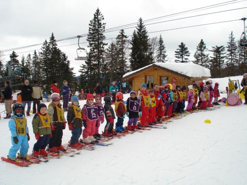 a group of children are lined up on skis in the snow at Chalet Monts Jura in Mijoux