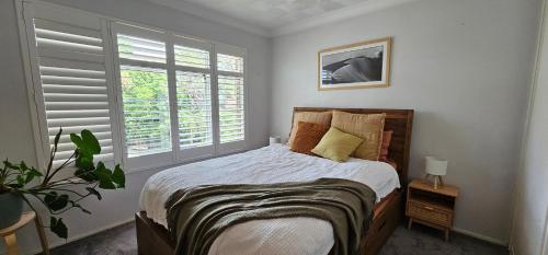 Un dormitorio con una cama y dos ventanas. en Lovley sunlit apartment walking distance to Cronulla mall and Cronulla Beach, en Cronulla