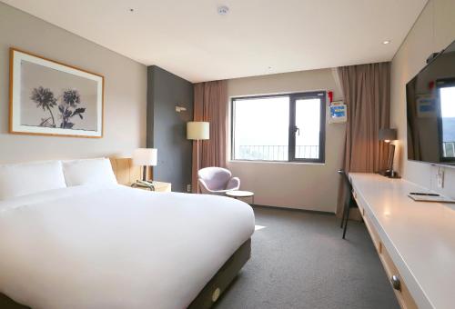 a hotel room with a large white bed and a desk at Eden Paradise Hotel in Icheon