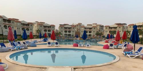 a pool at a resort with chairs and umbrellas at شاليه مصيفي فاخر قرية لاسيرينا الساحل الشمالي in Dawwār Ḩājj as Sayyid Rizq