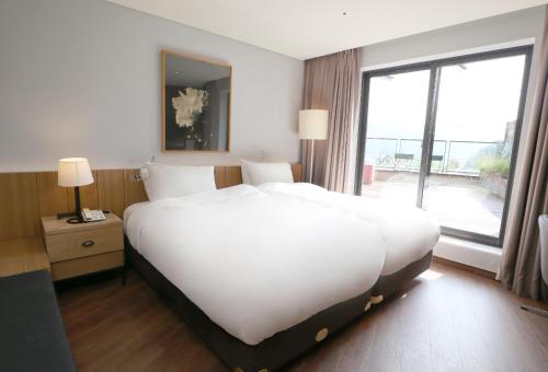 a large white bed in a hotel room with a window at Eden Paradise Hotel in Icheon