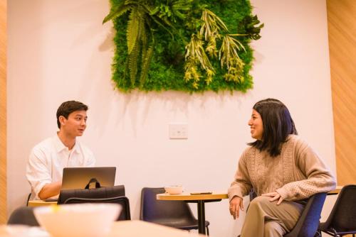a man and a woman sitting at a table with a laptop at &AND HOSTEL ASAKUSA KAPPABASHI in Tokyo