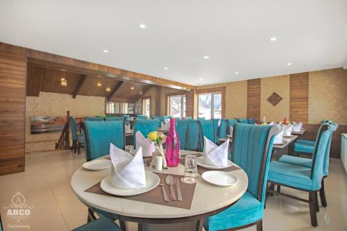 a dining room with a table and blue chairs at Arco Hotels & Resorts sonamarg in Sonāmarg