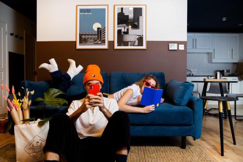 a man and a woman laying on a couch with a book and a phone at Bob W Tower of London in London