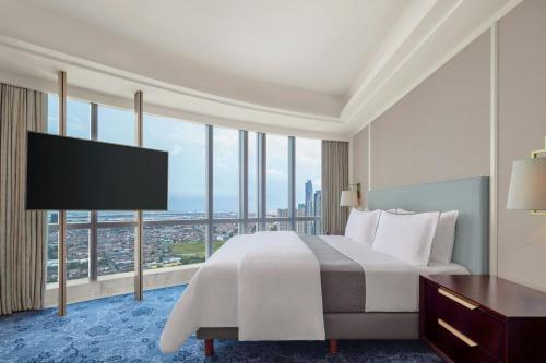 a bedroom with a large bed and a large window at The Westin Surabaya in Surabaya