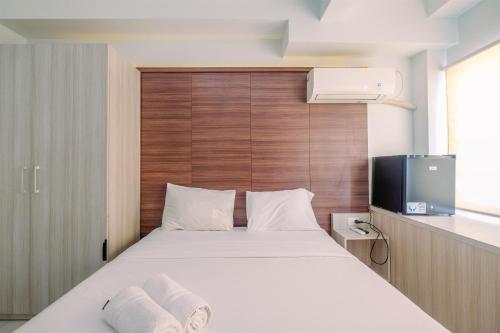 Un dormitorio con una cama blanca y un televisor. en Nice and Cozy Studio Apartment at Patraland Urbano By Travelio, en Bekasi