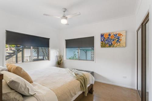 a white bedroom with a bed and two windows at Pearl of Scarborough in Scarborough