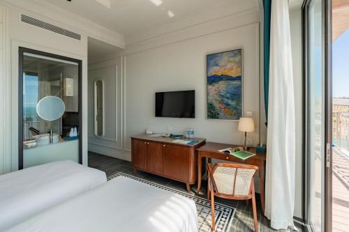 a hotel room with a desk and a television at Edensee Kega Beach Resort in Ke Ga