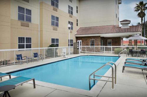 a swimming pool at a hotel with chairs and tables at TownePlace Suites Pensacola in Pensacola