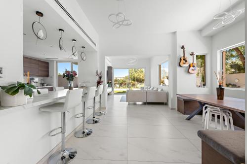 a kitchen with white walls and a dining room with white chairs at Elegant lakeside villa with a private pool in Dubai