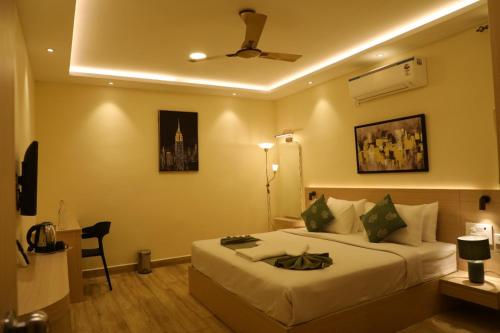 a hotel room with a bed and a ceiling fan at Hotel Green parrot in Madurai