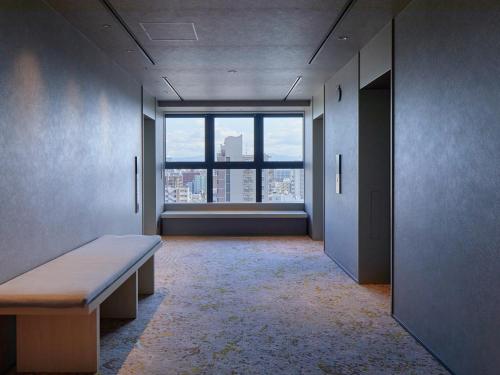 an empty room with a bench and a large window at Dorsett by Agora Osaka Sakai in Sakai
