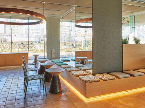a lobby with tables and chairs and large windows at Dorsett by Agora Osaka Sakai in Sakai