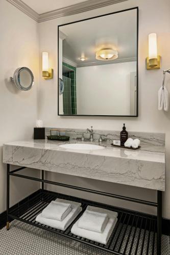 a bathroom with a sink and a large mirror at The Talbott, Autograph Collection in Chicago