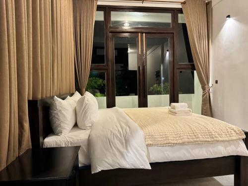 a bedroom with a white bed with a window at STONE AGE Boutique in Kampot