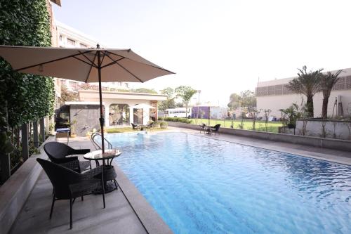 - Piscina con mesa y sombrilla en MARIGOLD-Newly Renovated Hotel, en Shirdi