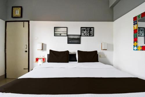 a bedroom with a large white bed with black pillows at Super Hotel O Swaranpuri Near KIIT Square in Bhubaneshwar