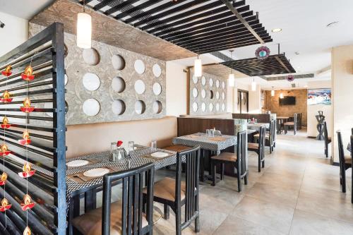 a restaurant with tables and chairs and a wall of plates at Palette Country Club Surat in Surat