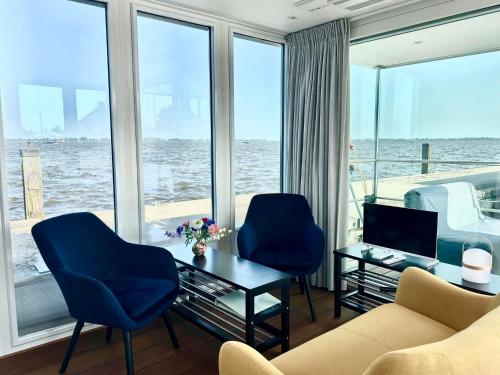 a living room with two chairs and a couch and a television at Houseboat Robbedoes in Offingawier