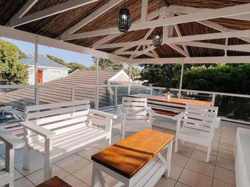 un patio con sedie e tavoli bianchi e un tavolo in legno di Wildecrest & Ripplemead, Amblewood Guesthouse a Kenton-on-Sea