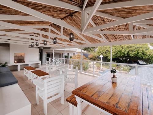 a living room with a wooden table and white chairs at Treetops, Amblewood Guesthouse in Kenton on Sea