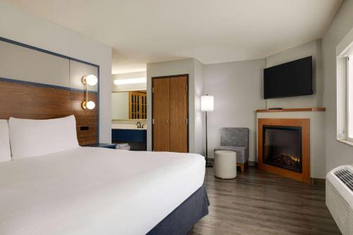 a hotel room with a large bed and a fireplace at AmericInn by Wyndham Lincoln South in Lincoln