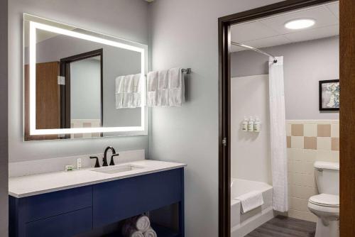 a bathroom with a sink and a mirror and a toilet at AmericInn by Wyndham Lincoln South in Lincoln