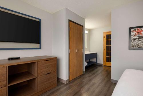 a bedroom with a large flat screen tv on a wall at AmericInn by Wyndham Lincoln South in Lincoln