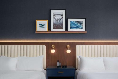 two beds in a hotel room with pictures on the wall at The Well House Hamilton, Tapestry Collection By Hilton in Hamilton