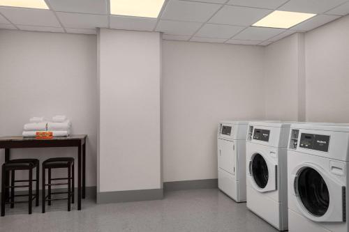 a laundry room with two washing machines and a table at The Well House Hamilton, Tapestry Collection By Hilton in Hamilton