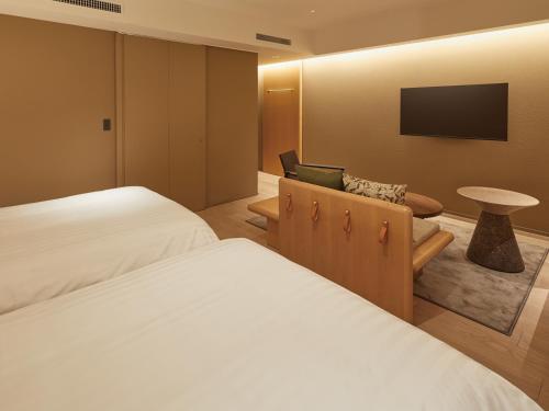 a hotel room with two beds and a chair at Dorsett by Agora Osaka Sakai in Sakai