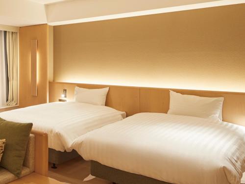 a hotel room with two beds and a chair at Dorsett by Agora Osaka Sakai in Sakai