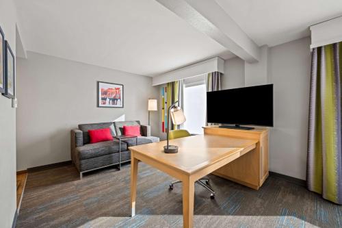 a living room with a desk and a flat screen tv at Hampton Inn & Suites Wilson I-95 in Wilson