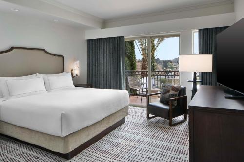 佩索罗伯斯Bellasera Hotel & Suites Paso Robles, Tapestry by Hilton的酒店客房设有一张床和一个阳台。