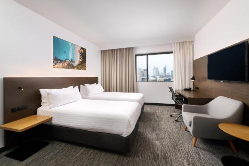 Una habitación de hotel con una cama, un escritorio y un televisor. en Holiday Inn West Perth by IHG, en Perth