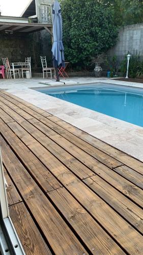 a wooden deck next to a swimming pool with an umbrella at Suite parentale in Saint-Pierre