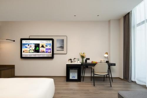 a living room with a table and a tv on the wall at Atour Hotel Hefei Binhu Yungu Financial City in Hefei