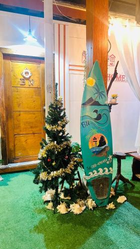 a surfboard sitting next to a christmas tree in a room at Bnเกาะลิบงโฮมสเตย์ in Ko Muk