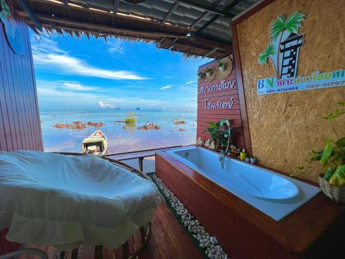 a bathroom with a tub and a view of the ocean at Bnเกาะลิบงโฮมสเตย์ in Ko Muk