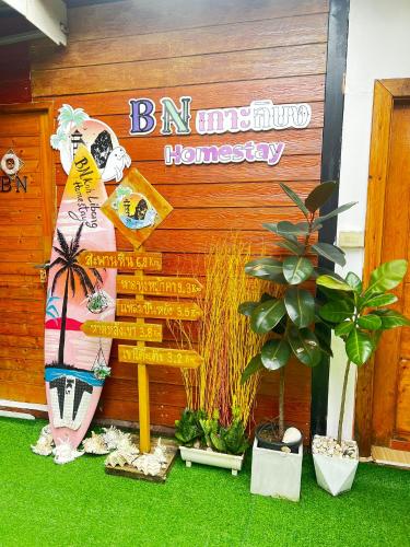 a sign in front of a building with plants at Bnเกาะลิบงโฮมสเตย์ in Ko Muk