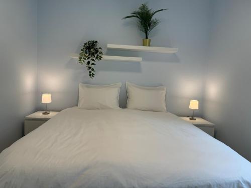 a bedroom with a large white bed with two lamps at Appartement NEUF, 6 personnes, 2 chambres in Ohligsmühle