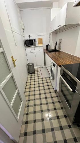 - une cuisine avec des placards blancs et un sol en damier dans l'établissement LE REX Nice, à Nice