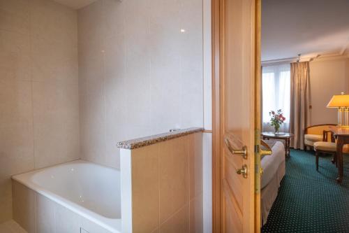 a bathroom with a bath tub and a bedroom at Domaine du Limonay, The Originals Collection in Saint-Méloir-des-Ondes