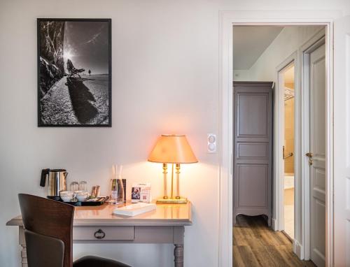 a desk with a lamp and a picture on the wall at Domaine du Limonay, The Originals Collection in Saint-Méloir-des-Ondes