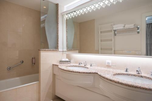 a bathroom with two sinks and a large mirror at Domaine du Limonay, The Originals Collection in Saint-Méloir-des-Ondes