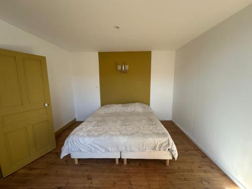 a small bedroom with a bed and a yellow door at Gite de la ferme des constant in Saint-Ignat