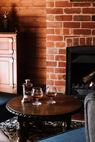 two wine glasses on a table in front of a fireplace at Kelly House in Beechworth