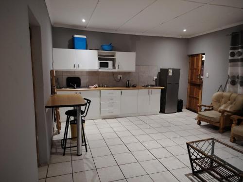 a kitchen with white cabinets and a table and a refrigerator at Self catering apartment in Vereeniging